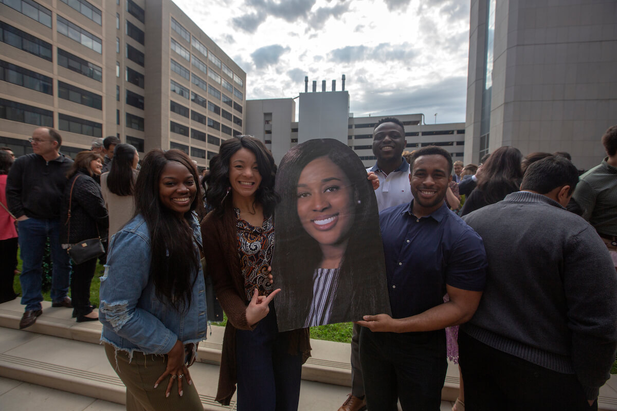 From left, Drew Dixson, Yakira Alford, Uyi Aisueni, and O’Brian Mbakwe, stand with a large cutout in support of their friend during Match Day at Baylor College of Medicine on March 15, 2019.