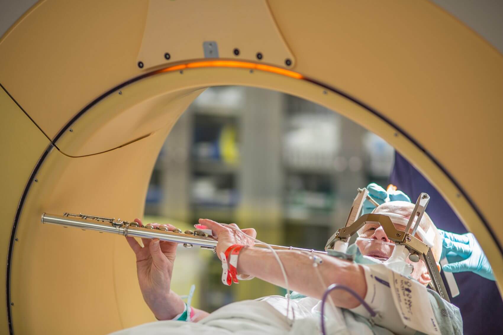 Deep brain stimulation patient Anna Henry plays the flute in the operating room bed.