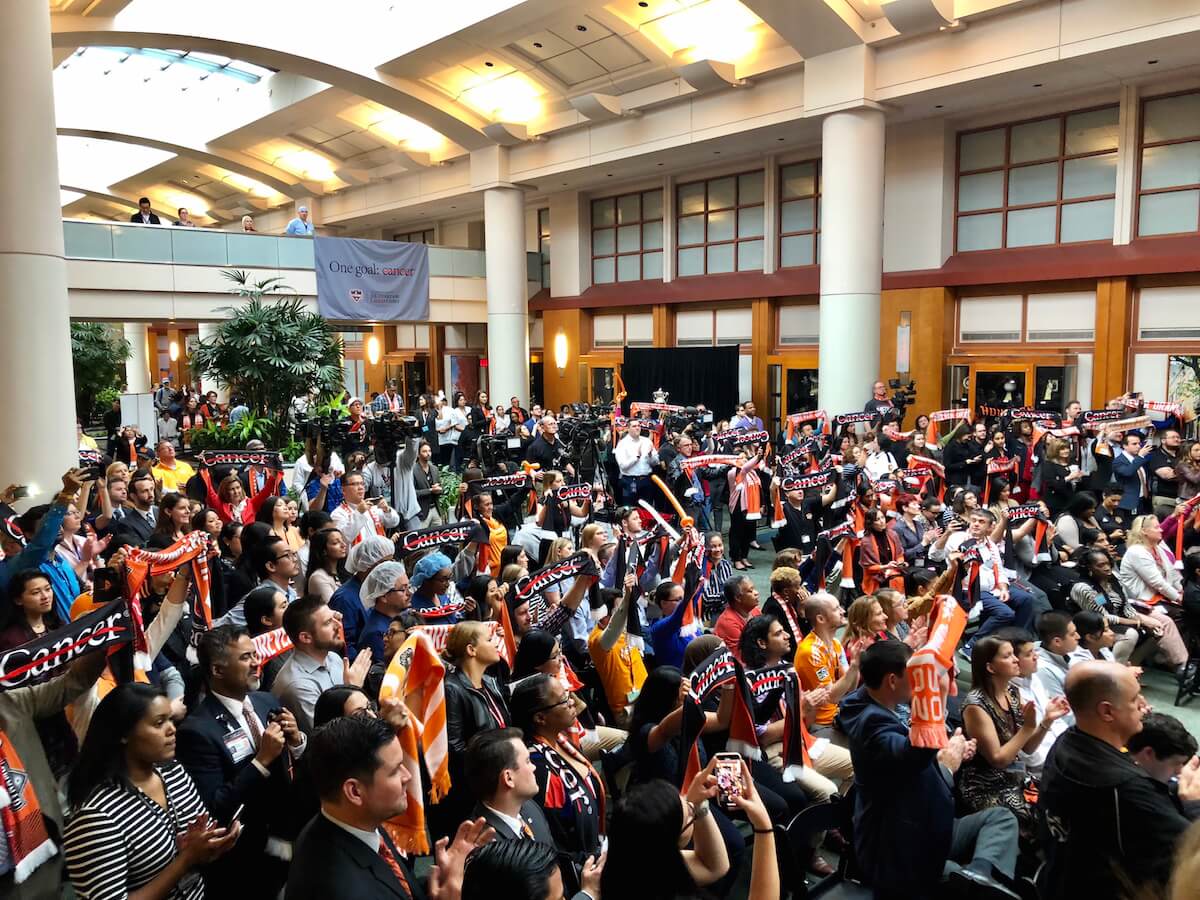 MD Anderson employees cheer as they watch pediatric and adult cancer survivors take their places for a symbolic “Starting XI” photo during the historic announcement.