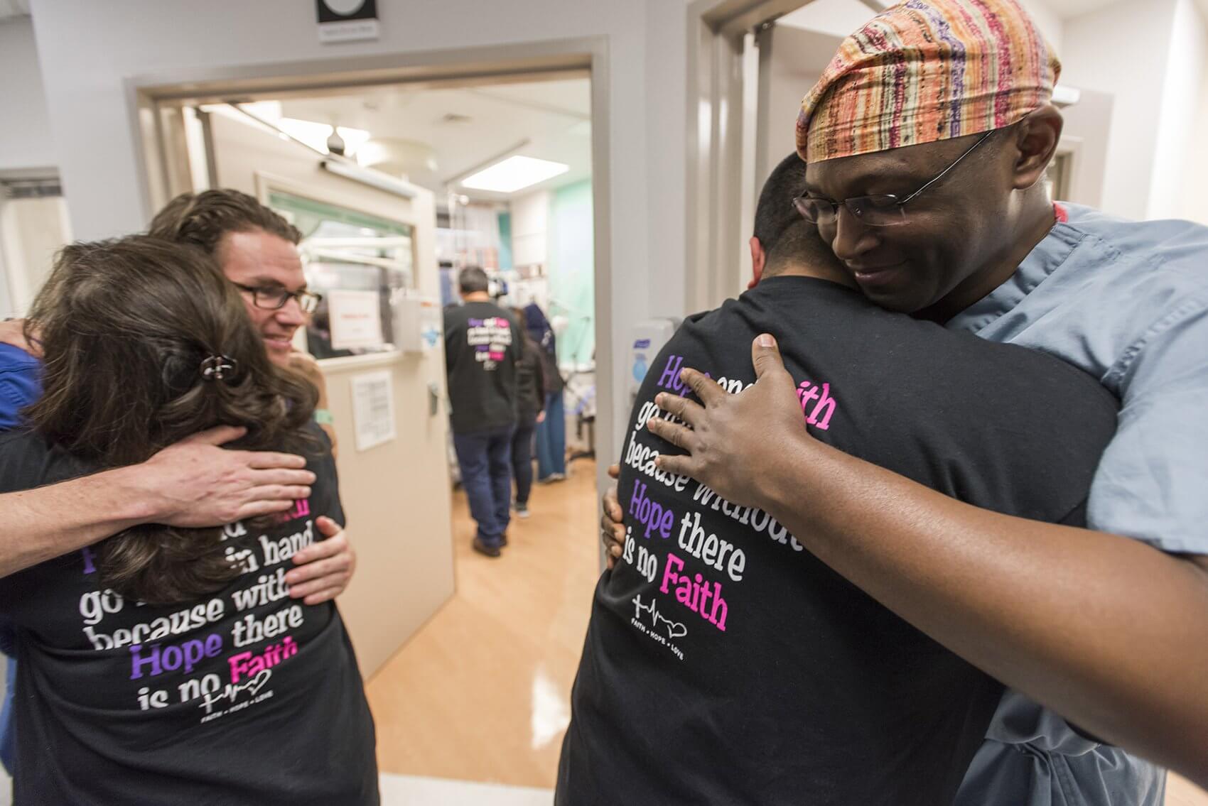 Edward Buchanan, M.D., and Oluyinka Olutoye, M.D., embrace the family after successful separation surgery. (Credit: Allen S. Kramer/Texas Children’s Hospital)