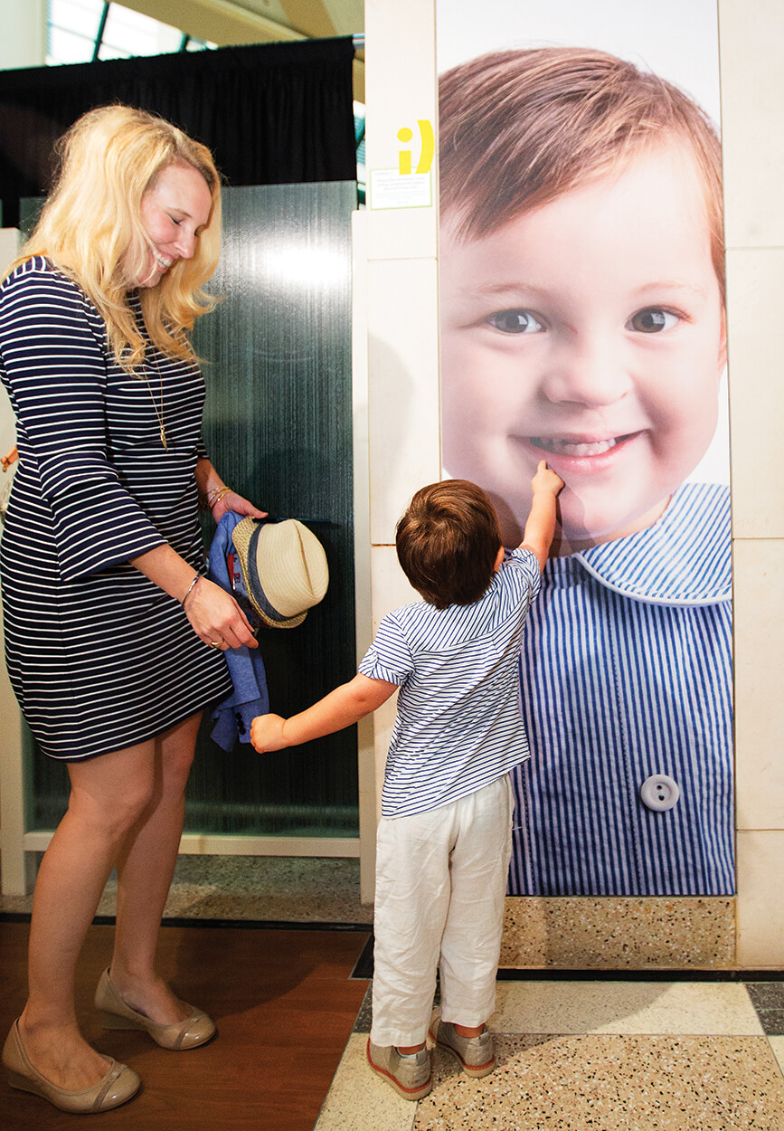 Whitney Hutchens looks on as her son, Charlie Adams, 3, admires his larger-than-life-size photo.
