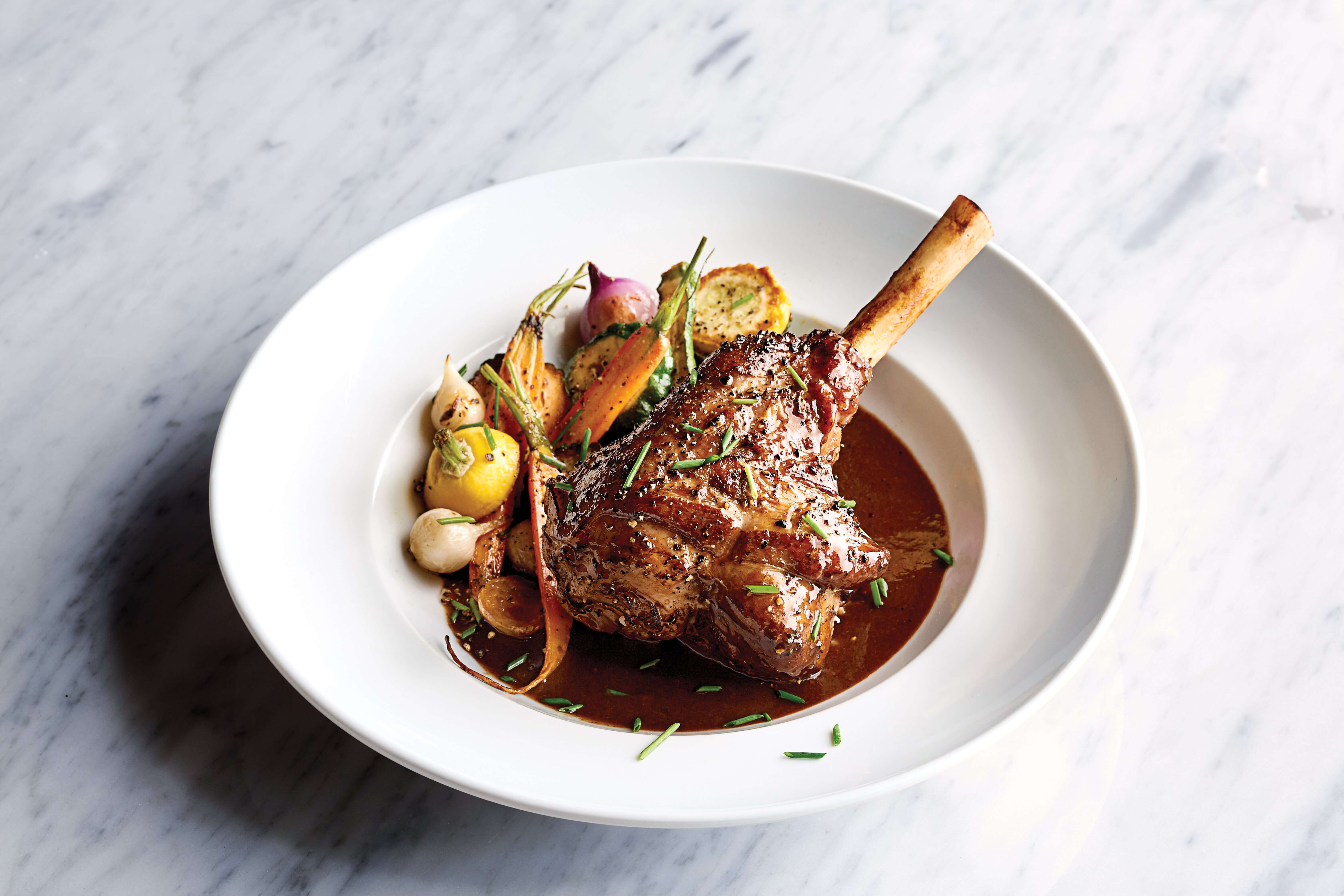 Pasture-raised lamb shank with marble potatoes, baby vegetables, and lamb reduction