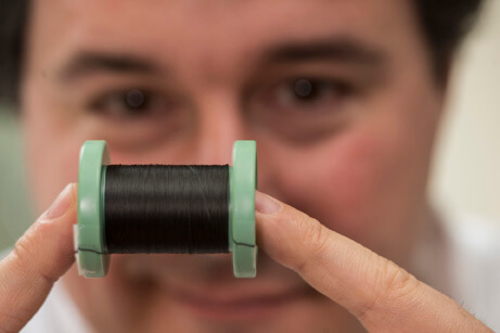 Rice scientist Matteo Pasquali holds a spool of fiber made of pure carbon nanotubes. The fibers are being studied to bridge gaps in the conductivity in damaged heart tissues. (Photo credit: Jeff Fitlow)
