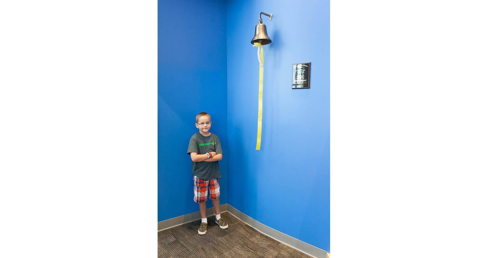 Ethan Williamson stands proudly next to the end of treatment bell after being the first patient to ring the new addition to Texas Children’s. (Credit: John R. Lewis Photography)