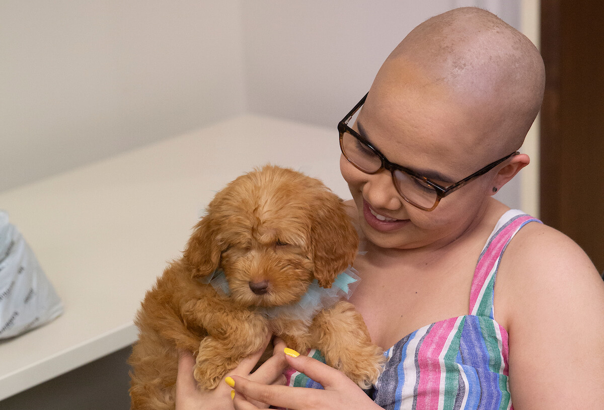 Cancer survivor and Ronald McDonald House Houston resident Paula Gómez Rodriguez, 19, of Puerto Rico, snuggles with Mateo, a 10-week-old Australian Labradoodle puppy granted to her by Stuff the Sleigh.