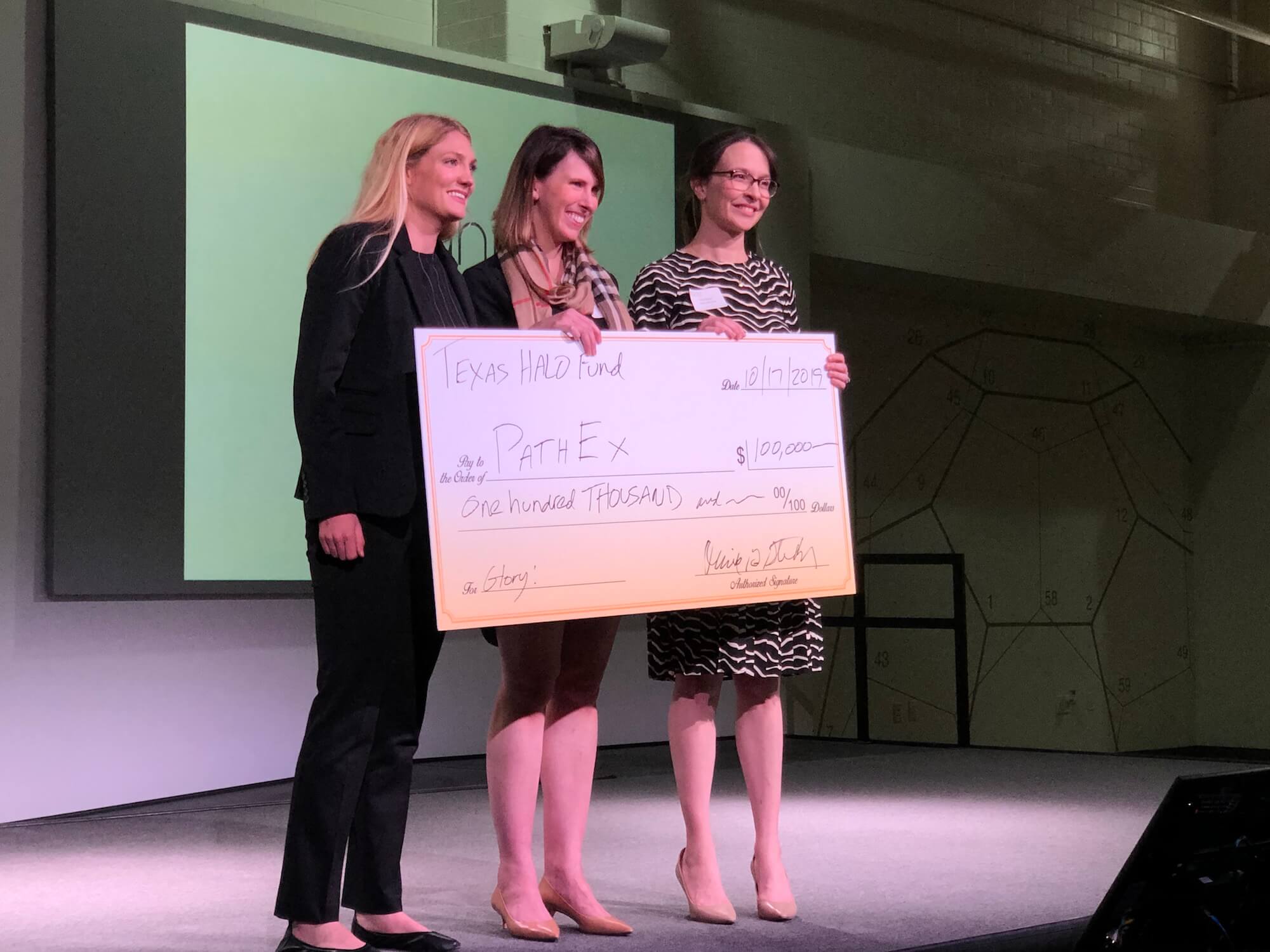 Sinead Miller, Ph.D., co-founder and CEO of PathEx (left) receives a $100,000 check from the Texas Halo Fund.
